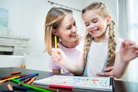 Happy mother and daughter hugging while drawing together at home